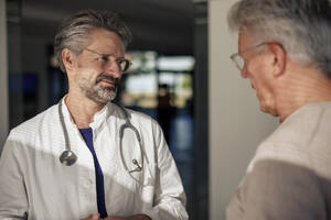 Lächelnder Arzt im Gespräch mit einem Mann im Krankenhaus - JOSEF21665