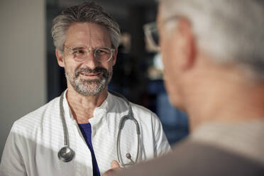Smiling senior doctor talking to man in hospital - JOSEF21667
