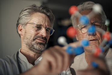 Senior scientist discussing with man over molecular structure - JOSEF21668