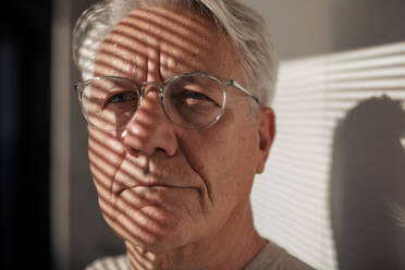 Senior man wearing eyeglasses with sunlight over face - JOSEF21687