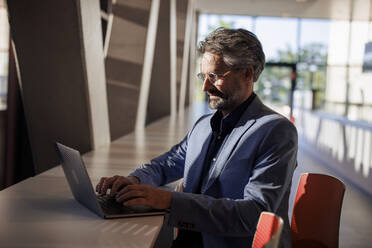 Geschäftsmann arbeitet am Laptop am Tisch - JOSEF21700