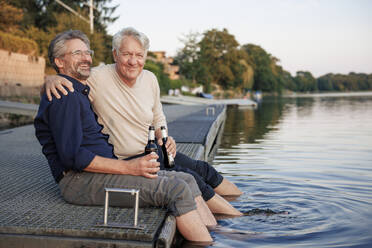 Glücklicher älterer Mann genießt ein Bier mit einem Freund auf dem Bootssteg - JOSEF21717