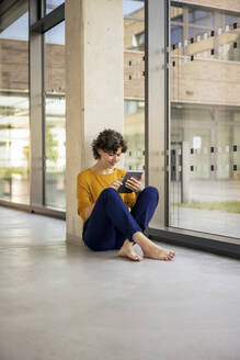 Junge Geschäftsfrau mit Tablet-PC in der Nähe eines Glasfensters - JOSEF21733