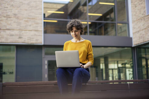 Geschäftsfrau arbeitet an einem Laptop vor einem Gebäude - JOSEF21744
