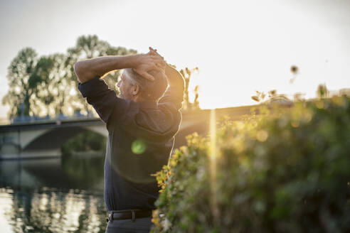 Man standing with head in hands at sunset - JOSEF21826