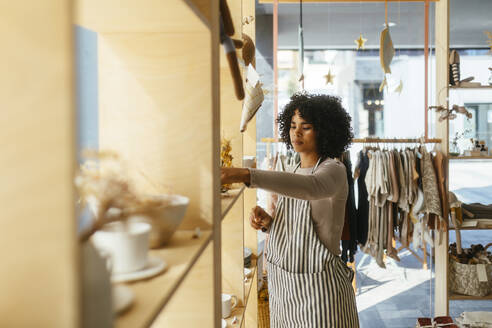 Owner wearing apron arranging products in store - EBSF03938