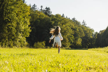 Happy girl running in front of trees in meadow - NDEF01227