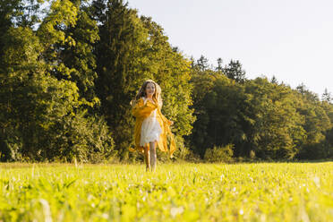 Happy girl running in front of trees on grass - NDEF01237
