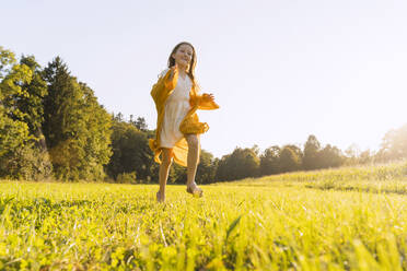 Cheerful girl running on grass in field - NDEF01238