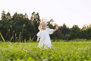 Smiling blond girl running in front of trees - NDEF01264