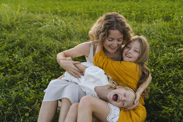 Happy mother enjoying with daughters on grass - NDEF01267