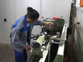 Jugendlicher Auszubildender bei der Prüfung einer Drehmaschine in der Werkstatt - CVF02594