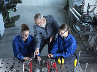 Ausbilder, der Auszubildende bei der Verwendung von CNC-Werkzeugen in der Werkstatt unterstützt - CVF02601