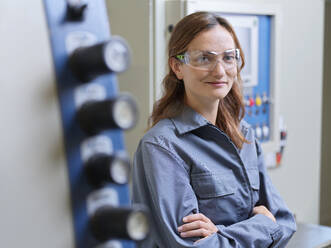 Smiling young woman with arms crossed at workshop - CVF02602