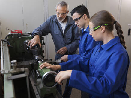 Trainees learning to operate lathe machine with instructor at workshop - CVF02604