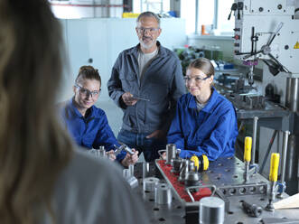 Lächelnder Ausbilder mit jungen Auszubildenden beim Workshop - CVF02606