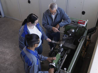 Ausbilder erklärt Auszubildenden in der Werkstatt die Drehmaschine - CVF02609