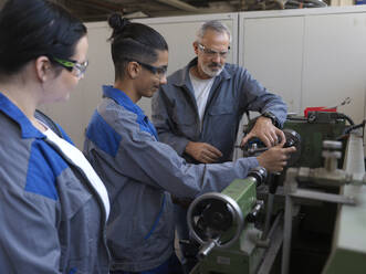 Trainees learning to use lathe machine with instructor at workshop - CVF02612