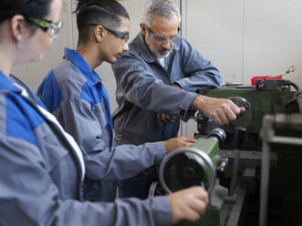 Instructor giving lathe machine training to trainees at workshop - CVF02613