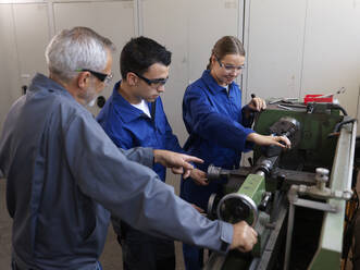 Young trainees using lathe machine with instructor at workshop - CVF02614