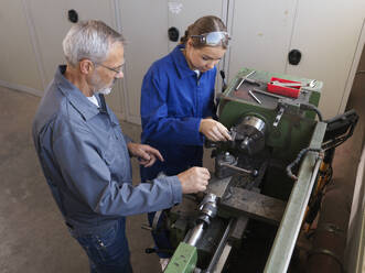 Ausbilder unterrichtet Auszubildende an der Drehmaschine in der Werkstatt - CVF02618