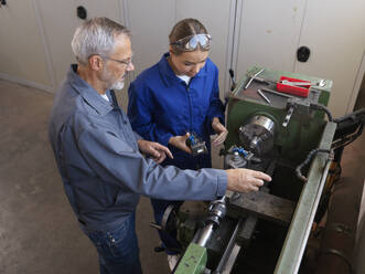 Ausbilder bei der Ausbildung eines Lehrlings an einer Drehmaschine in der Werkstatt - CVF02619