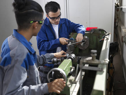 Teenage apprentices using lathe machine at workshop - CVF02629