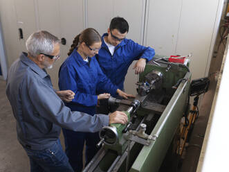 Instructor assisting trainees operating lathe at workshop - CVF02642