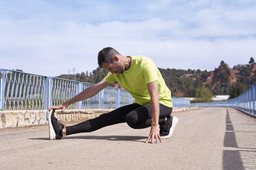 Man doing stretching leg exercise on bridge - VEGF06211