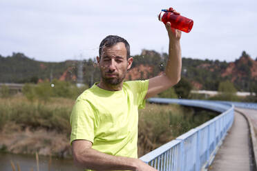 Man splashing water on face through bottle - VEGF06219