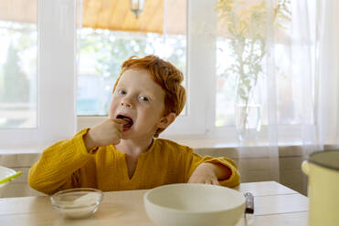 Junge isst Zucker am Tisch in der Küche - MBLF00038