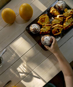 Junge nimmt Muffin vom Teller auf dem Tisch zu Hause - MBLF00048