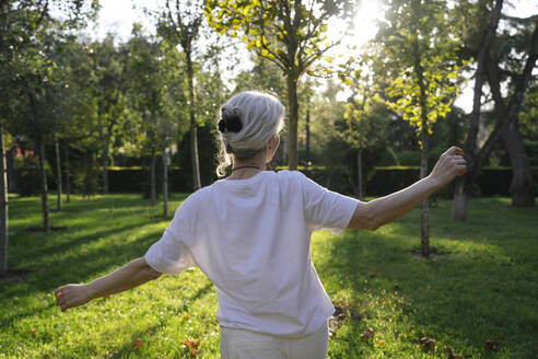 Mature woman with arms outstretched enjoying in park - YBF00272