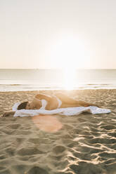 Frau auf Decke liegend am Strand unter Himmel - SIF01037