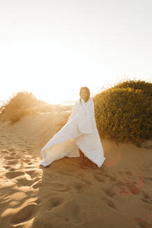 Frau in Decke eingewickelt am Strand stehend - SIF01058