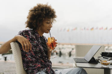 Junge Frau trinkt und benutzt einen Tablet-PC am Tisch - BOYF02004