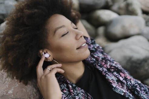 Young woman relaxing and listening to music through wireless In-ear headphones - BOYF02053