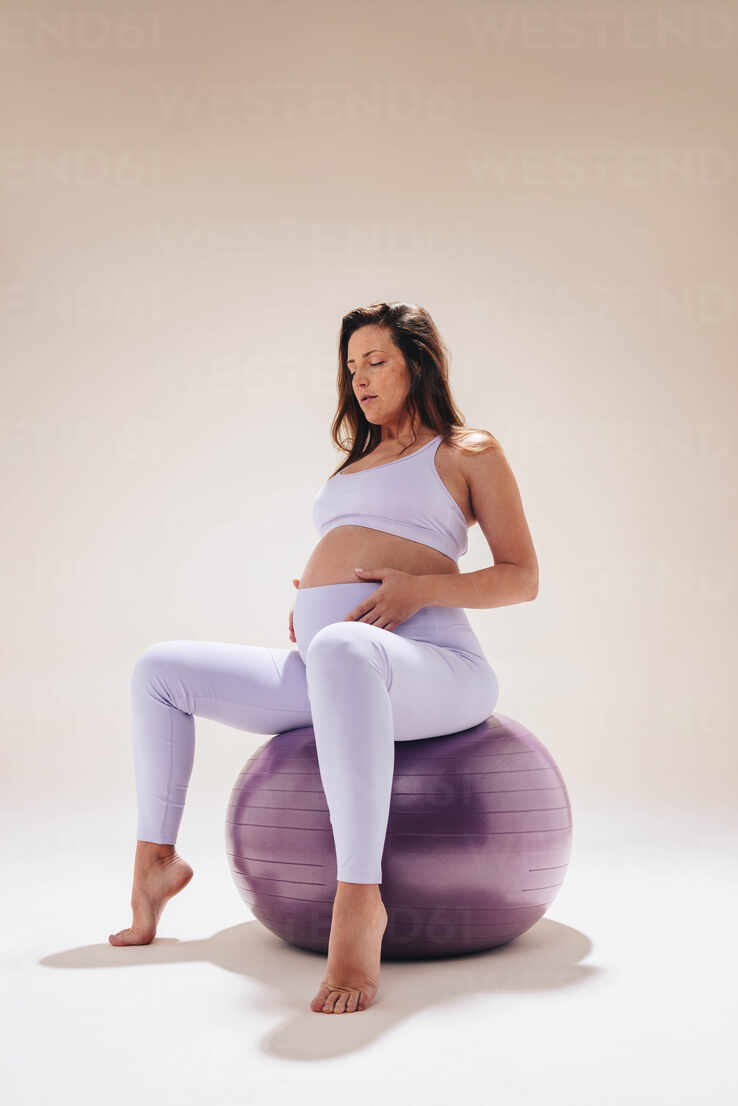 Pregnant woman in her third trimester practices prenatal yoga in a