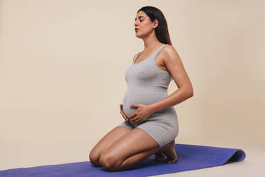 Home workout pregnant woman squatting doing leg workout squat with fitness  online class standing on yoga mat. Pregnancy prenatal exercise Stock Photo  by ©Maridav 565458244