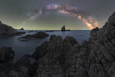 Picturesque landscape of rocks and mountains near calm sea under blue sky with Milky Way at night - ADSF48656