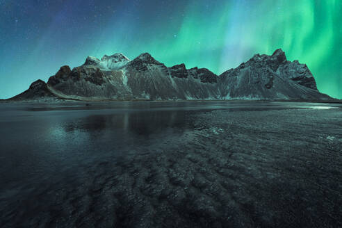 Picturesque view of frozen surface of water and small mountain ridge on background of amazing polar lights - ADSF48671