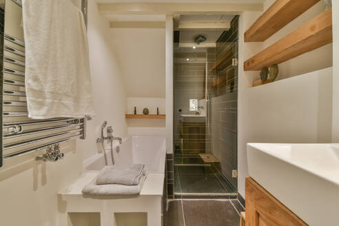 Interior of bathroom with shower cabin and ceramic bathtub with sink in modern apartment with white walls - ADSF48716