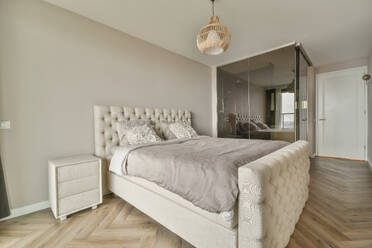 Interior of spacious bedroom with comfortable bed and glass shower cabin in modern apartment with white walls - ADSF48723