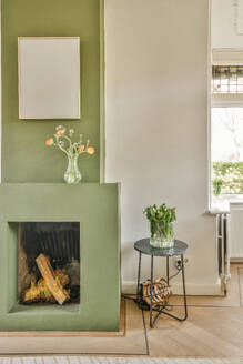 Flower vases on mantle over fireplace and table with picture frame hanging on wall in contemporary apartment - ADSF48733