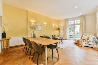 Comfortable sofas and wooden dining table with chairs arranged in living room at modern apartment with yellow wall - ADSF48742