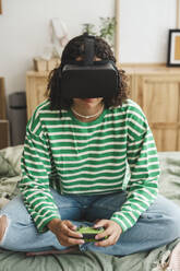 Mädchen trägt Virtual-Reality-Simulatoren und spielt ein Videospiel mit Controller zu Hause - ALKF00661