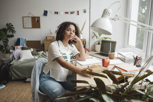 Teenager-Mädchen mit Büchern sitzt am Schreibtisch im Schlafzimmer - ALKF00686