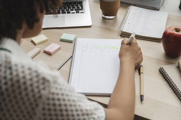 Teenage girl making notes on notepad at desk - ALKF00688