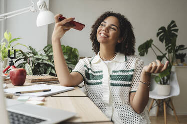 Happy girl talking on mobile phone at desk - ALKF00692