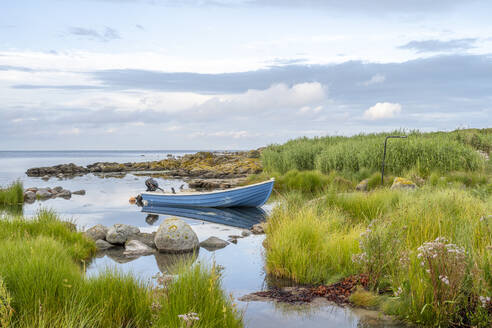Dänemark, Bornholm, Svaneke, Motorboot am grasbewachsenen Ufer der Insel vertäut - KEBF02753
